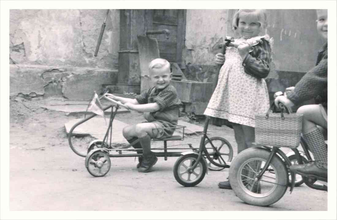 Kindergruppe beim Spiel mit dem Dreirad, dem Roller und dem Kinderfahrrad im Hof des Hauses Wienerstraße 3- Schranz/Pani