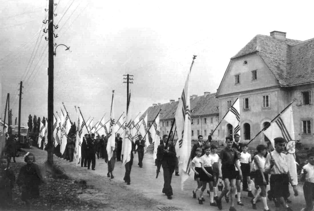 Festzug mit Fahnen der Kath. Jugend vor der Südtiroler Siedlung (Wienerstaße 28)