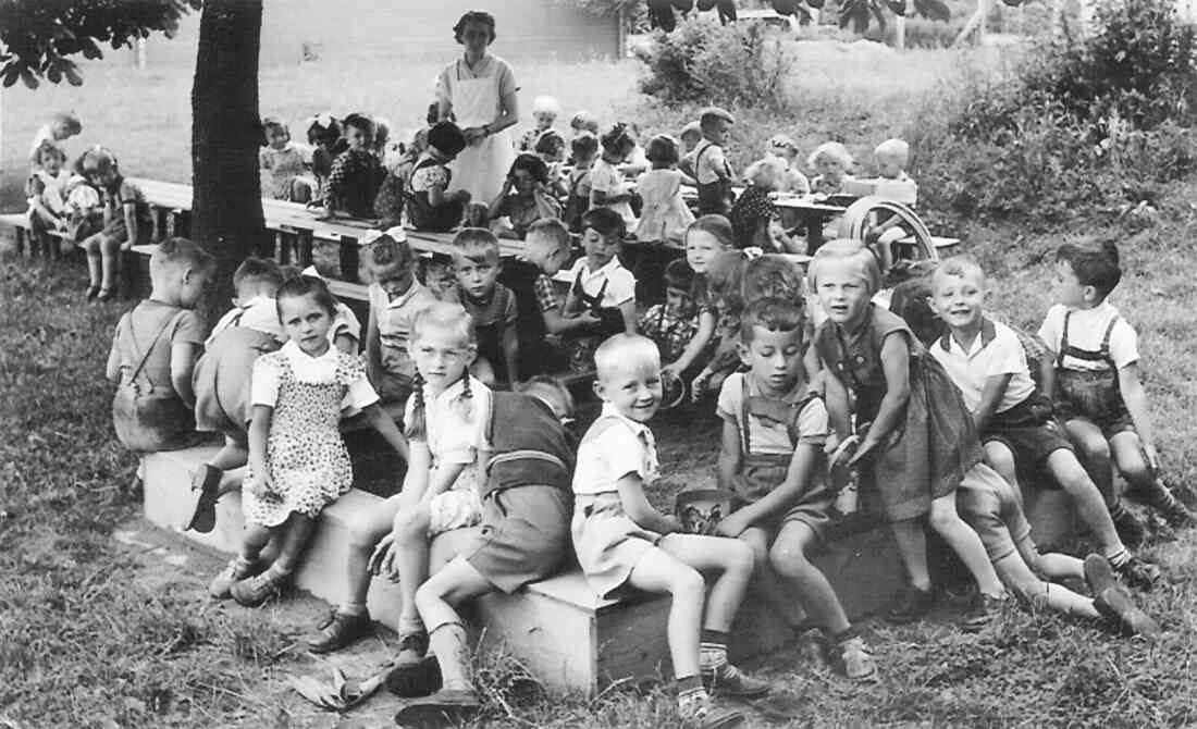 Gruppe des städtischen Kindergartens im Garten - Sandkiste und an den Tischen