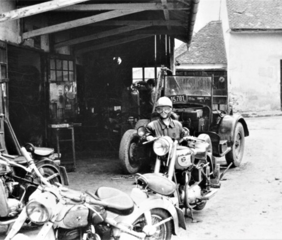 Reparaturwerkstätte Palank: Rainer Palank und der Blick auf die Motorräder vor dem Betriebsgebäude gegen NW
