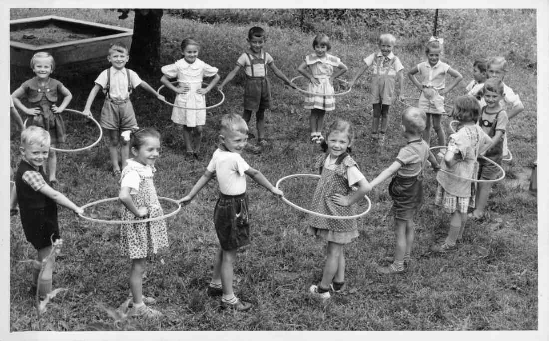 Gruppe des städtischen Kindergartens mit Hula-Hoop-Reifen und Pädagogin "Tante Grete" Schmaldienst